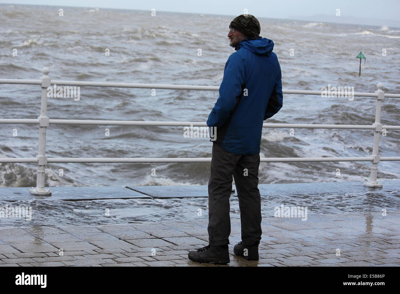 Un uomo si erge su Aberystwyth promenade durante le tempeste invernali del 2014 Foto Stock