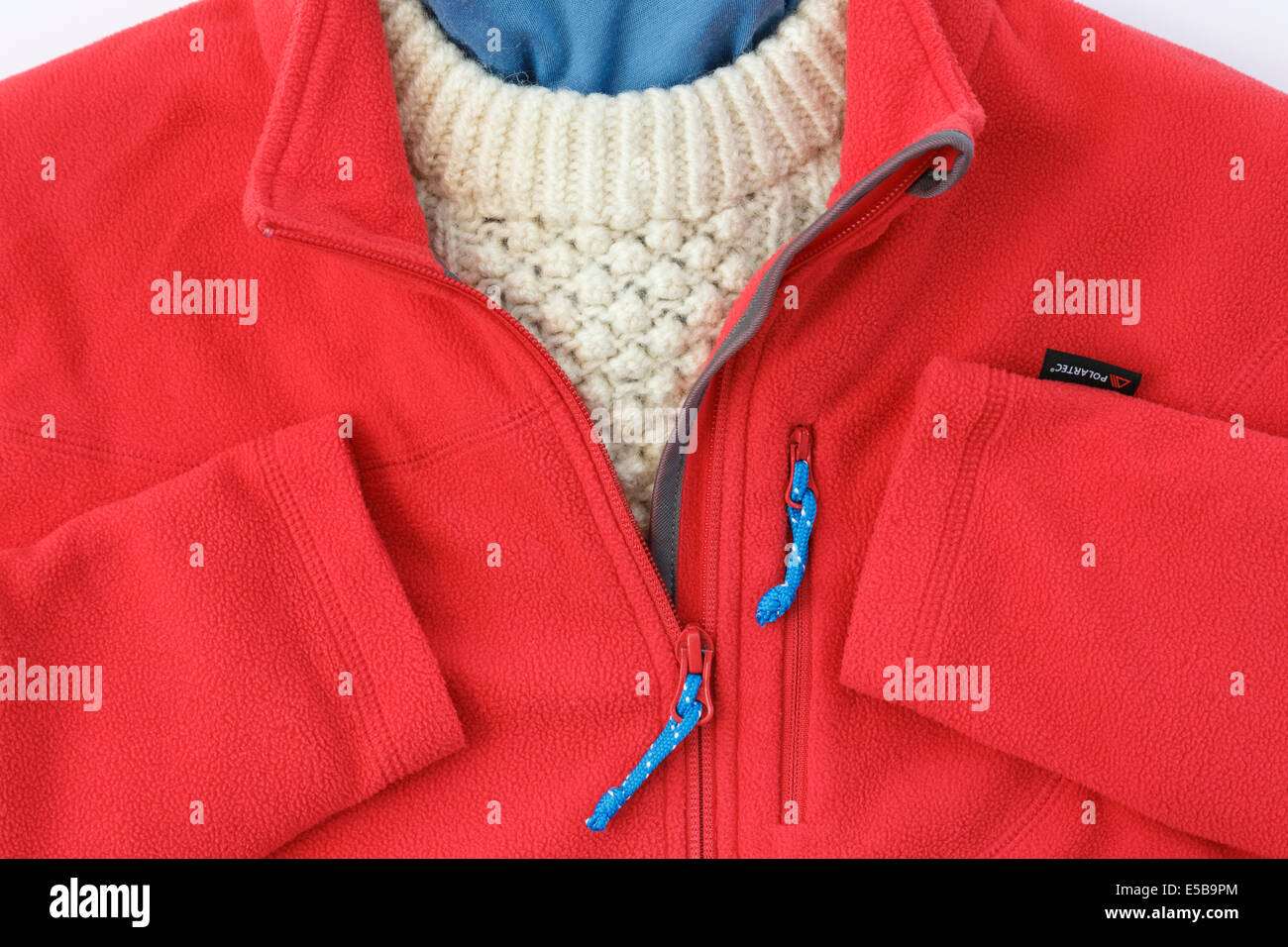 Rosso vello Polartec giacca con zip aperto sopra un maglione di Arran per il caldo abbigliamento invernale. Inghilterra, Regno Unito, Gran Bretagna Foto Stock