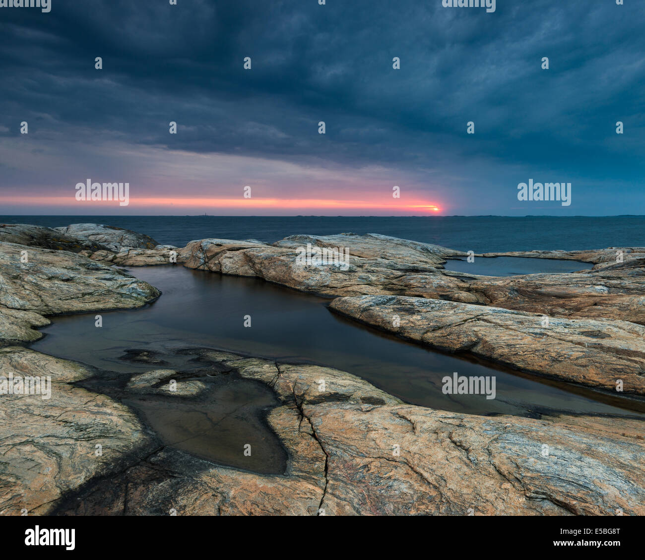 Costa rocciosa con drammatica cielo durante il tramonto Foto Stock