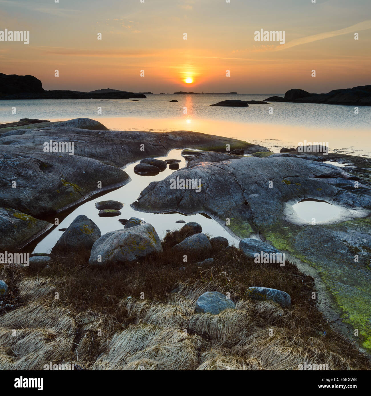 Spiaggia rocciosa e idilliaco con mare al tramonto Foto Stock