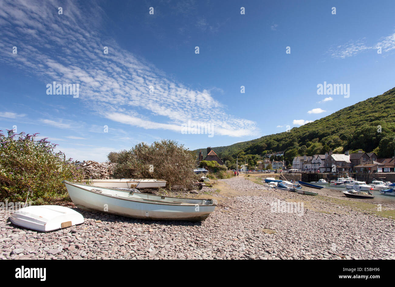 Piccole imbarcazioni giacciono sulla spiaggia di ciottoli a Porlock Weir, una popolare destinazione turistica nel sud ovest dell'Inghilterra. Foto Stock