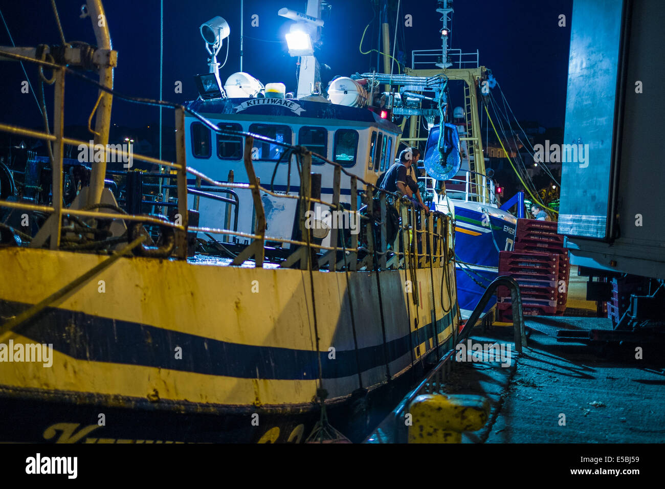 Peschereccio sbarcano le proprie catture a crepuscolo serale a Howth Pier, Dublin, Repubblica d'Irlanda. Foto Stock