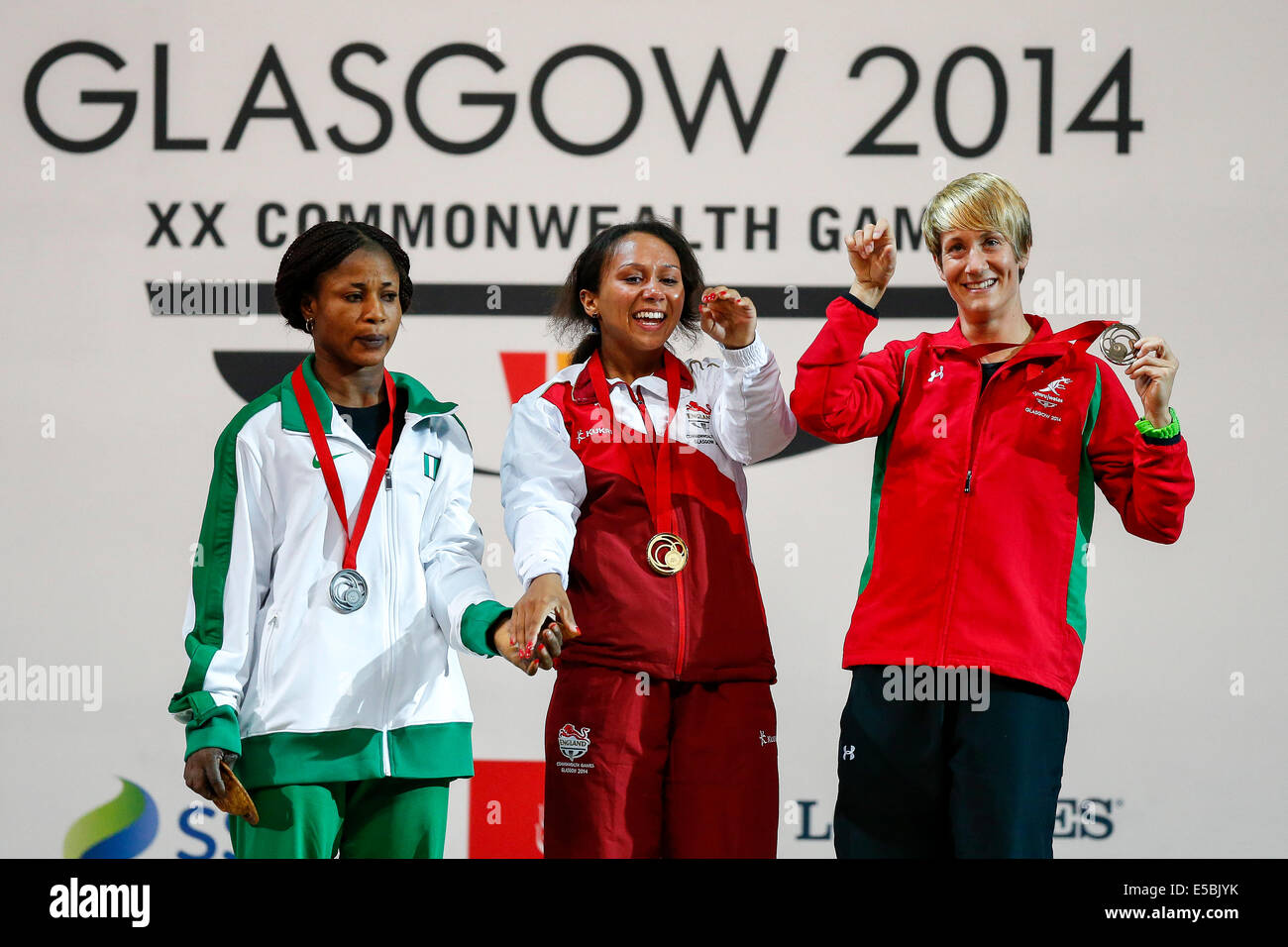 Glasgow, Scozia. 26 Luglio, 2014. Glasgow 2014 Giochi del Commonwealth il giorno 3. Sollevamento pesi. Zoe Smith di Inghilterra festeggia sul podio con uno sconsolato cercando runner-up Winifred Ndidi della Nigeria e bronzo medallist Michaela brezza del Galles dopo aver vinto la medaglia d'oro nella Womens 58kg Gruppo un finale. Credito: Azione Sport Plus/Alamy Live News Foto Stock