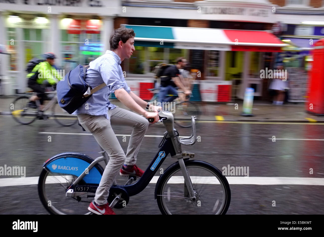 Ciclista su Boris bike durante un clima umido a Londra Foto Stock