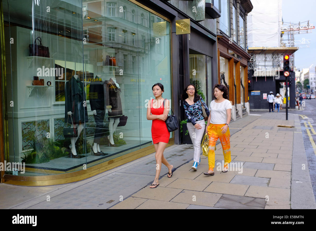 Attraente giovane donna cinese in rosso mini abito con le donne anziane su Bond Street Foto Stock