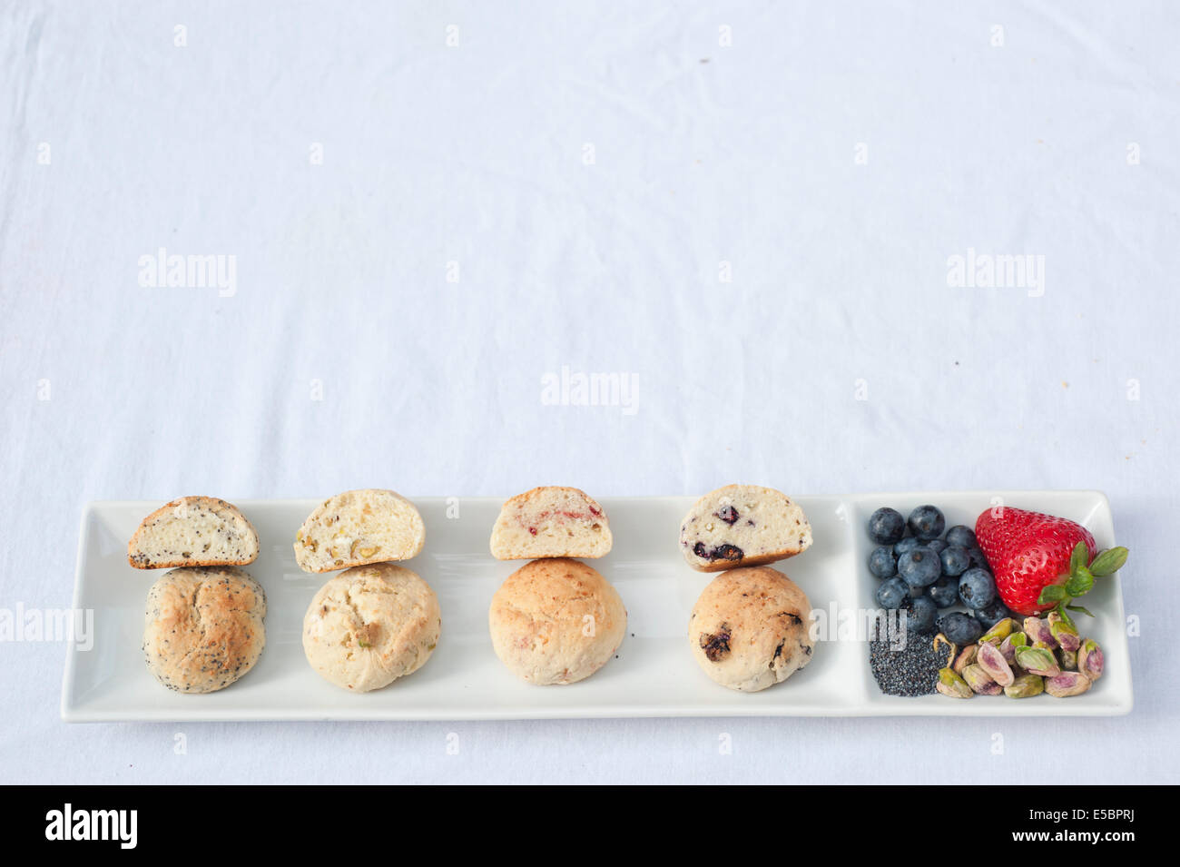 Un set di quattro biscotti affettato aperto placcato su un piatto bianco accanto ai principali ingredienti che sono stati utilizzati in ciascuna di esse. Foto Stock