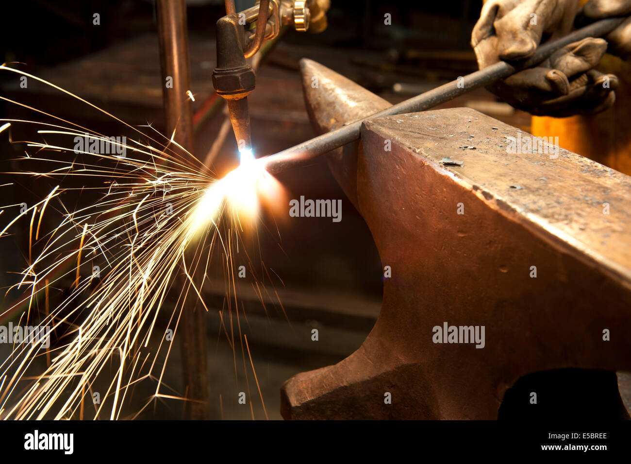 Un costruttore di metallo utilizzando una torcia a calore di un pezzo di metallo per dare forma a. Foto Stock