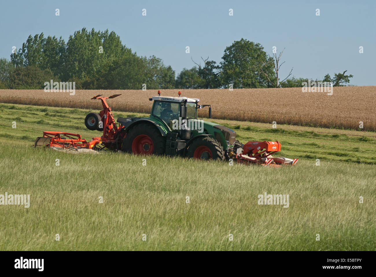 Trattore tirando l'erba-cutter taglio di erba per la produzione di fieno Foto Stock