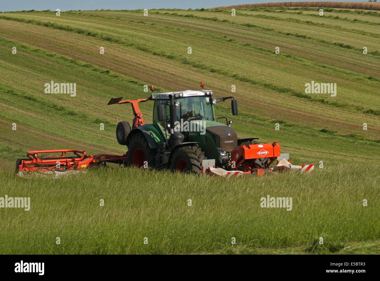 Trattore tirando l'erba-cutter taglio di erba per la produzione di fieno Foto Stock