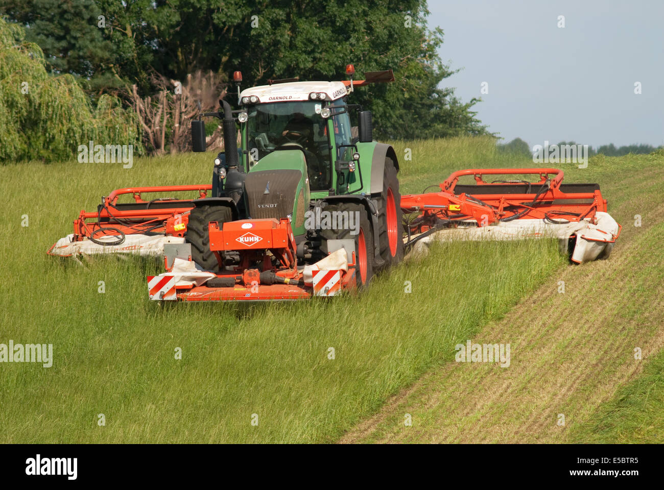Trattore tirando l'erba-cutter taglio di erba per la produzione di fieno Foto Stock