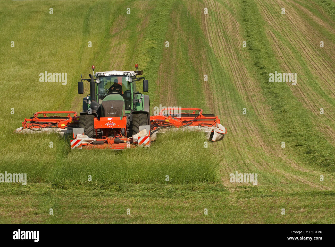 Trattore tirando l'erba-cutter taglio di erba per la produzione di fieno Foto Stock