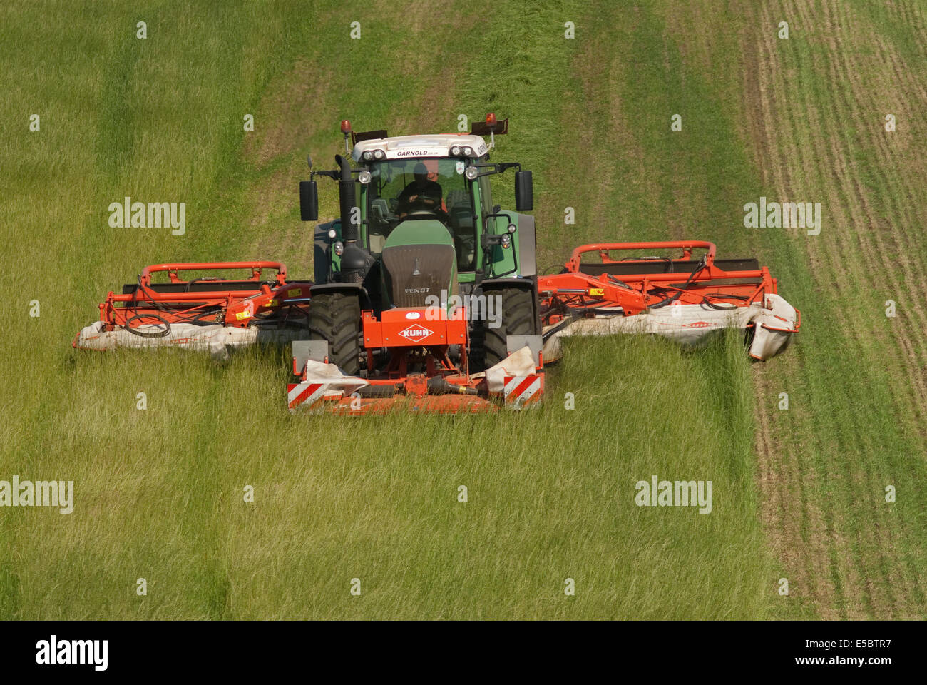 Trattore tirando l'erba-cutter taglio di erba per la produzione di fieno Foto Stock