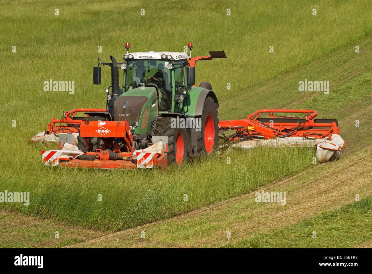 Trattore tirando l'erba-cutter taglio di erba per la produzione di fieno Foto Stock