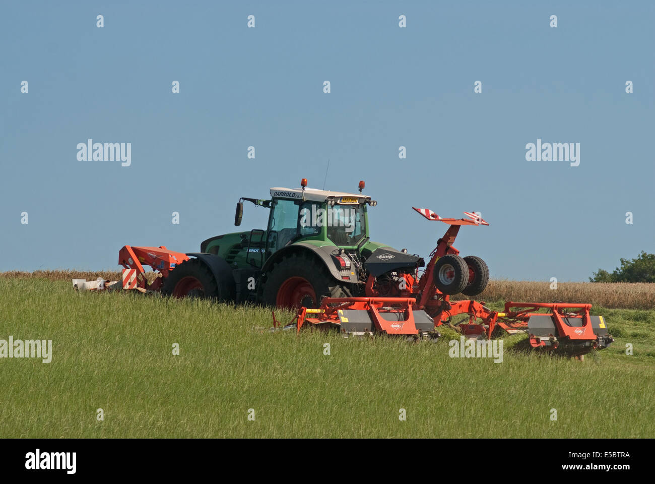 Trattore tirando l'erba-cutter taglio di erba per la produzione di fieno Foto Stock
