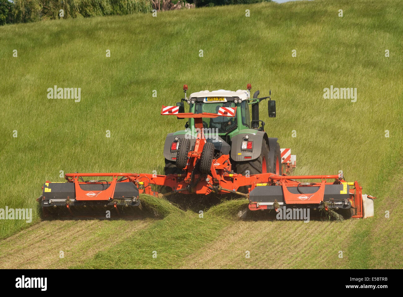Trattore tirando l'erba-cutter taglio di erba per la produzione di fieno Foto Stock