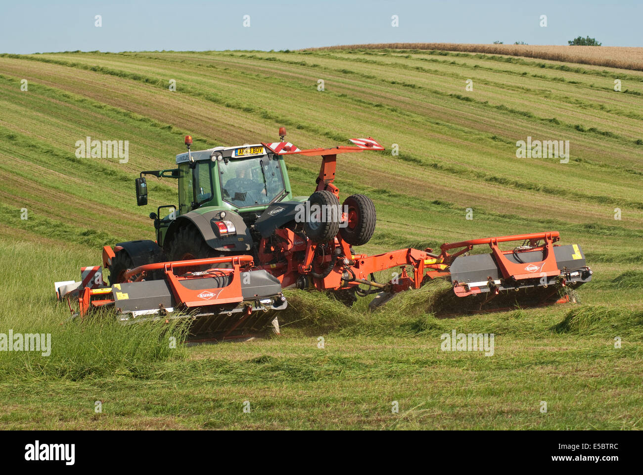 Trattore tirando l'erba-cutter taglio di erba per la produzione di fieno Foto Stock