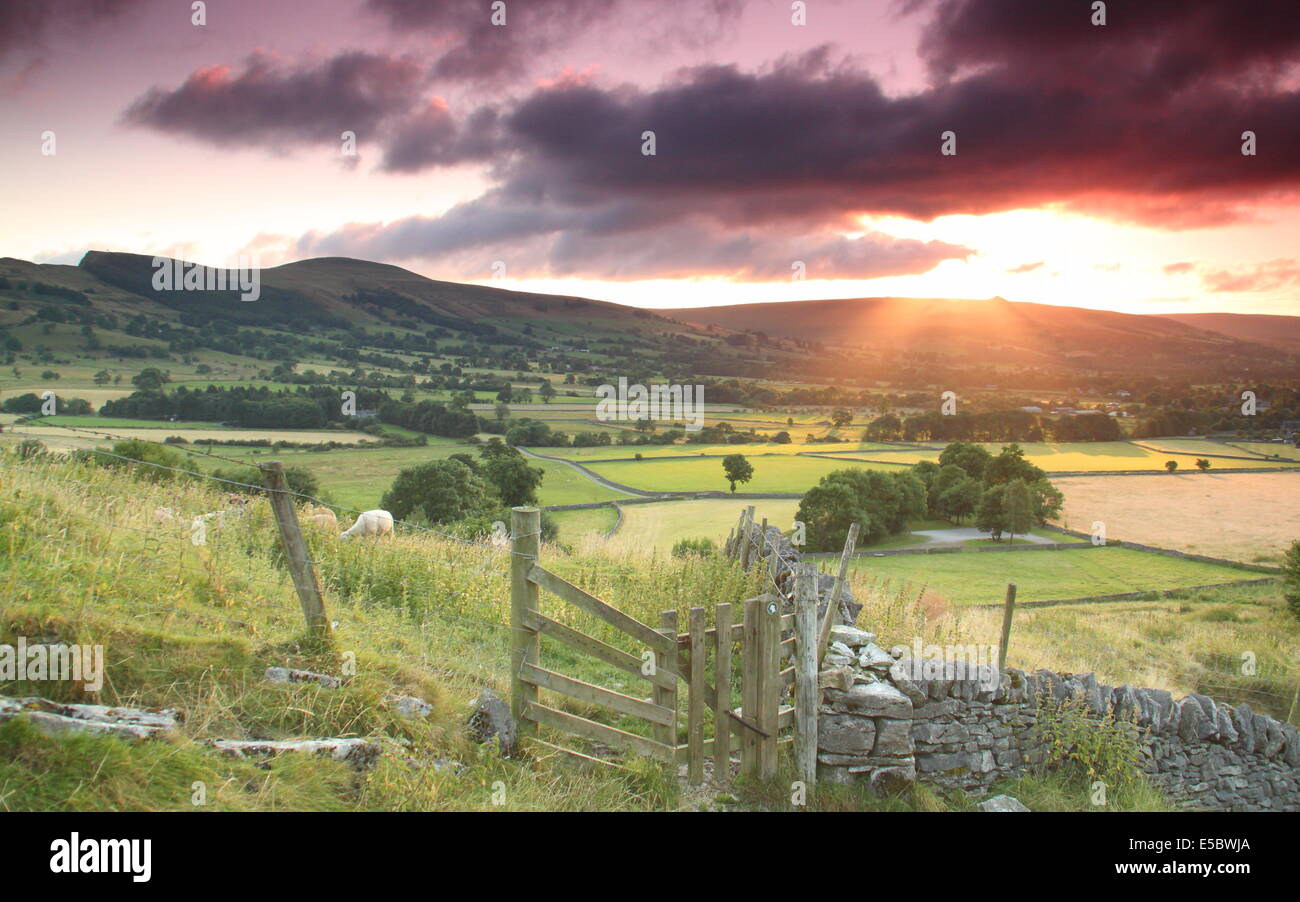 Il Peak District, Derbyshire, Regno Unito. Il 27 luglio 2014. Una che ricordano le pesche alba illumina le nuvole scure scudding su Hope Valley vicino a Castleton nel Parco Nazionale di Peak District su una bella e ariosa mattina. La recente è molto caldo è previsto di continuare a con la variabile cloud, docce e più incantesimi di pioggia che colpiscono parti del Regno Unito nel corso di Parchi Nazionali Settimana che inizia domani (lunedì 28 luglio) e gira fino a quando Sun 3 Agosto. Il Peak District divenne Gran Bretagna il primo parco nazionale in 1951. Credito: Matthew Taylor/Alamy Live News Foto Stock