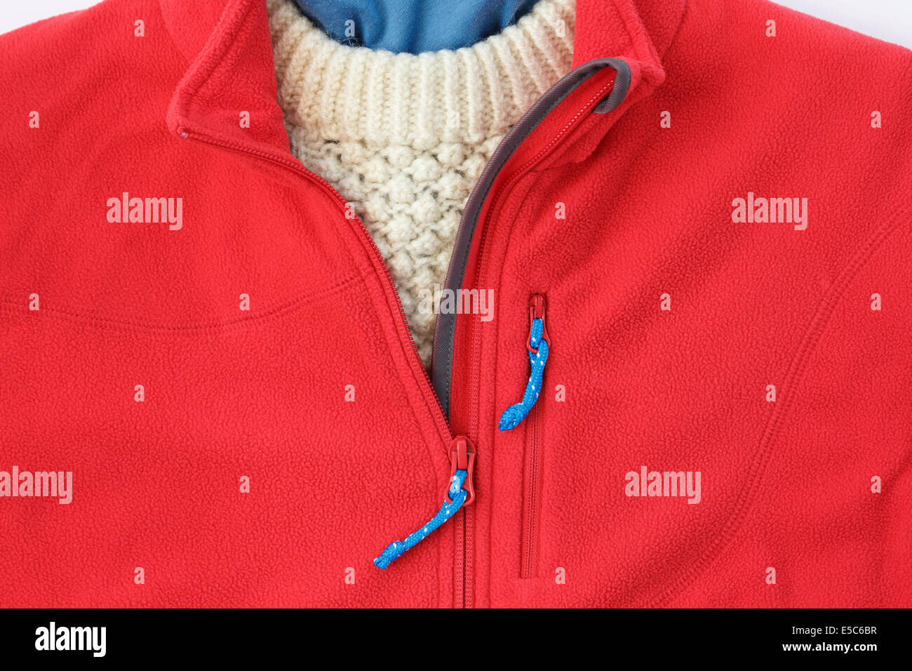 Persona che indossa un'accogliente giacca in pile rosso con zip aperta su un pullover Arran per un abbigliamento invernale caldo. Inghilterra, Regno Unito, Gran Bretagna Foto Stock