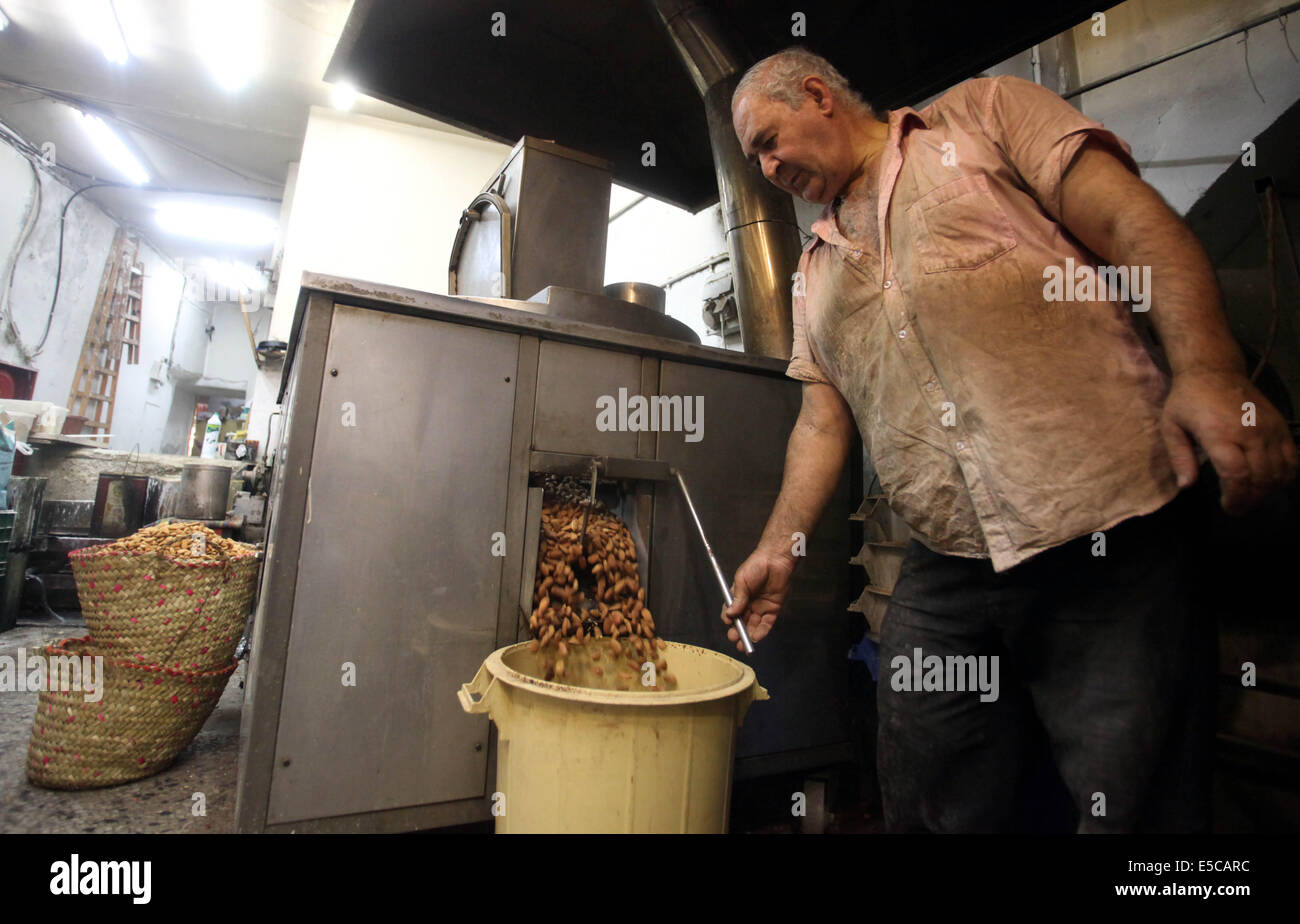 Luglio 27, 2014 - Gerusalemme, Gerusalemme, Territorio palestinese - un uomo palestinese prepara i dadi per la preparazione per la prossima Eid al-Fitr festival, in un mercato di Gerusalemme il 27 luglio 2014. Eid al-Fitr festival è accolto come un triste Eid tra palestinesi da parte delle forze israeliane rinnovato è incursioni su Gaza, che a seguito di una 24 ore di tregua, uccisi nove palestinesi, sollevando il pedaggio complessivo da 20 giorni di funzionamento per più di 1.050. Sami Abu Zuhri senior portavoce per l'organizzazione palestinese Hamas ha detto a detto, ''In risposta a un intervento delle Nazioni Unite e tenendo conto della situazione del nostro popolo e th Foto Stock