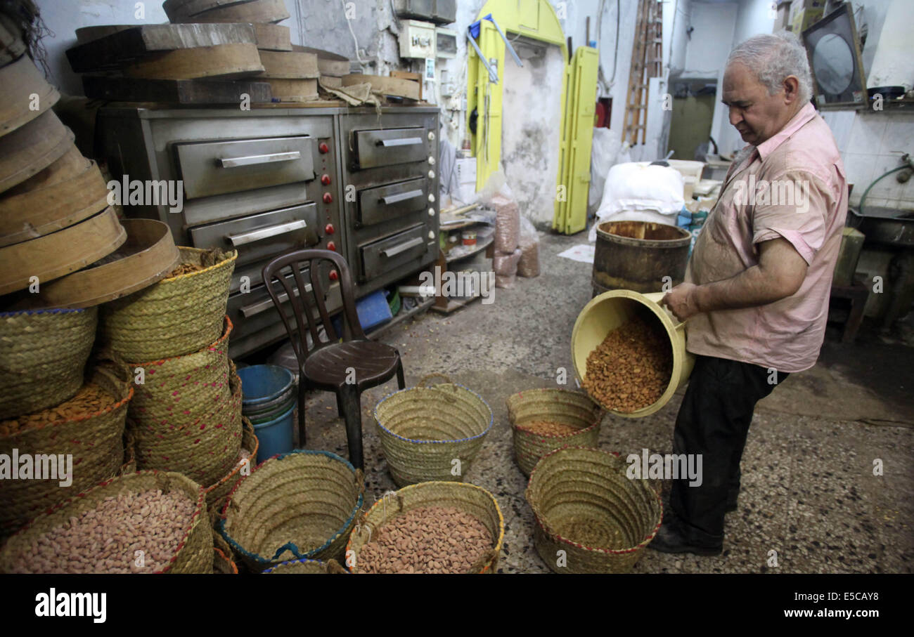 Luglio 27, 2014 - Gerusalemme, Gerusalemme, Territorio palestinese - un uomo palestinese prepara i dadi per la preparazione per la prossima Eid al-Fitr festival, in un mercato di Gerusalemme il 27 luglio 2014. Eid al-Fitr festival è accolto come un triste Eid tra palestinesi da parte delle forze israeliane rinnovato è incursioni su Gaza, che a seguito di una 24 ore di tregua, uccisi nove palestinesi, sollevando il pedaggio complessivo da 20 giorni di funzionamento per più di 1.050. Sami Abu Zuhri senior portavoce per l'organizzazione palestinese Hamas ha detto a detto, ''In risposta a un intervento delle Nazioni Unite e tenendo conto della situazione del nostro popolo e th Foto Stock