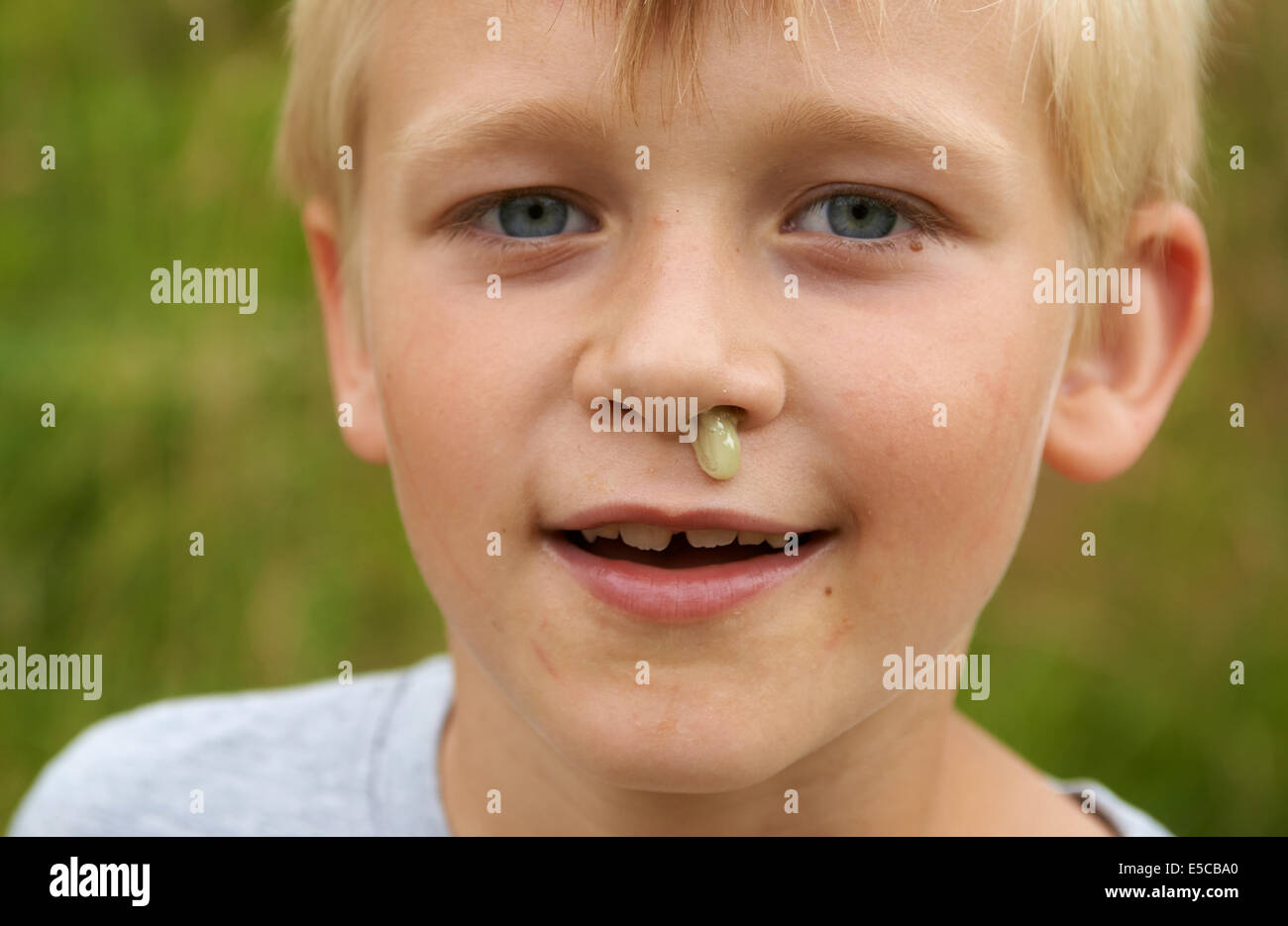 Bambino ragazzo biondo con rinite senza tessuto fluente dal naso, ritratto, colpo alla testa, viso, dettaglio Foto Stock