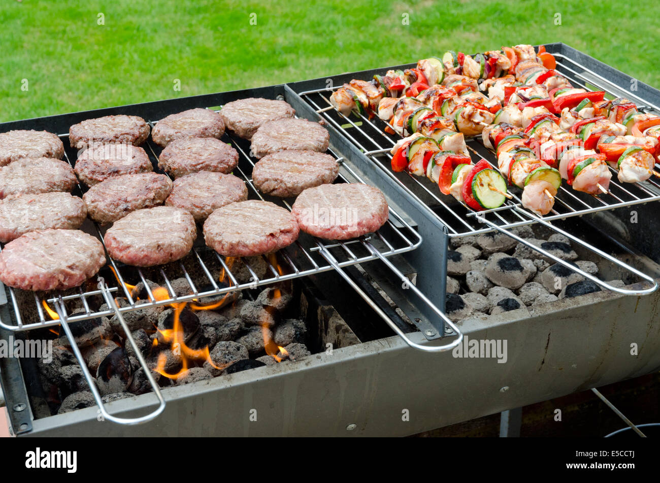 Barbecue a carbone per barbecue caricato con spiedini di pollo e hamburger di manzo Foto Stock