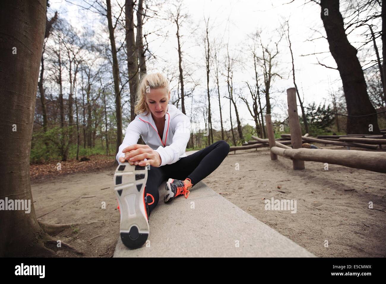 Montare donna stretching le gambe prima di correre. Caucasian modello femminile che esercitano nel parco. Foto Stock