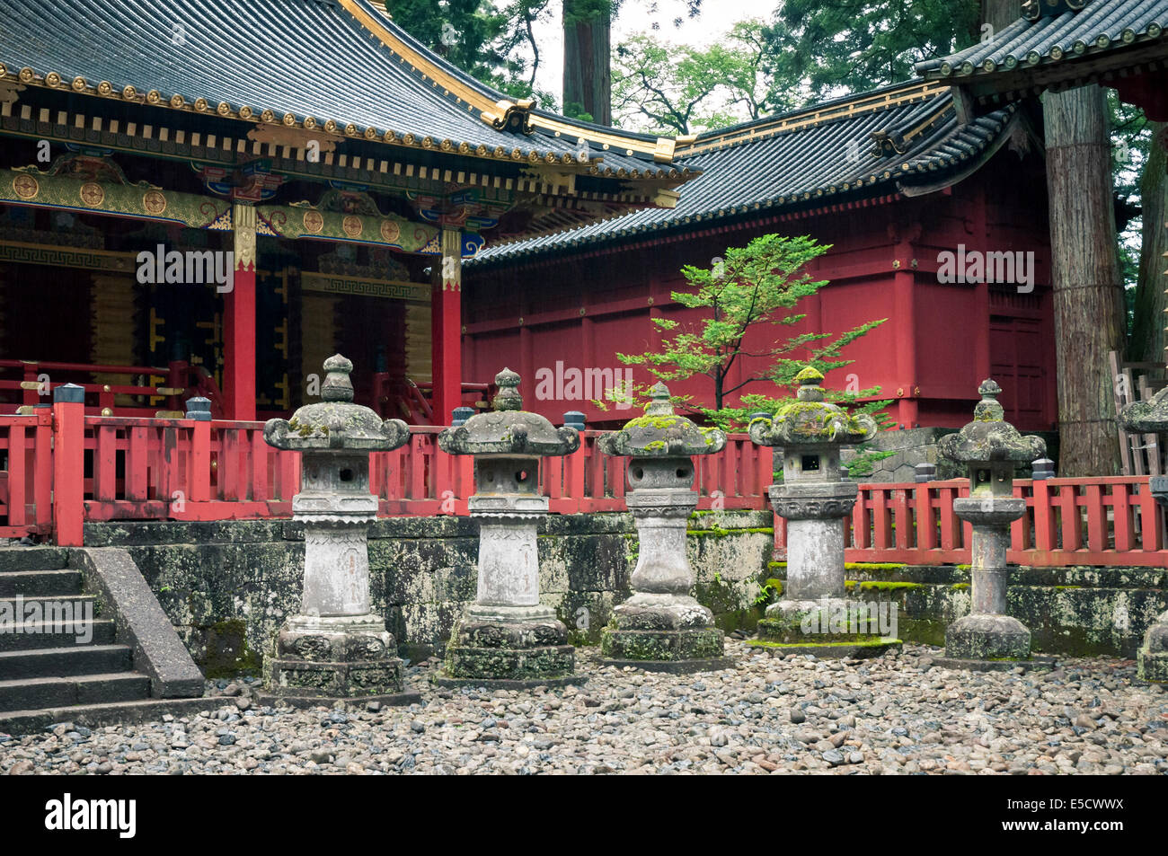 Antiche lanterne di pietra con tempio giapponese dietro Foto Stock