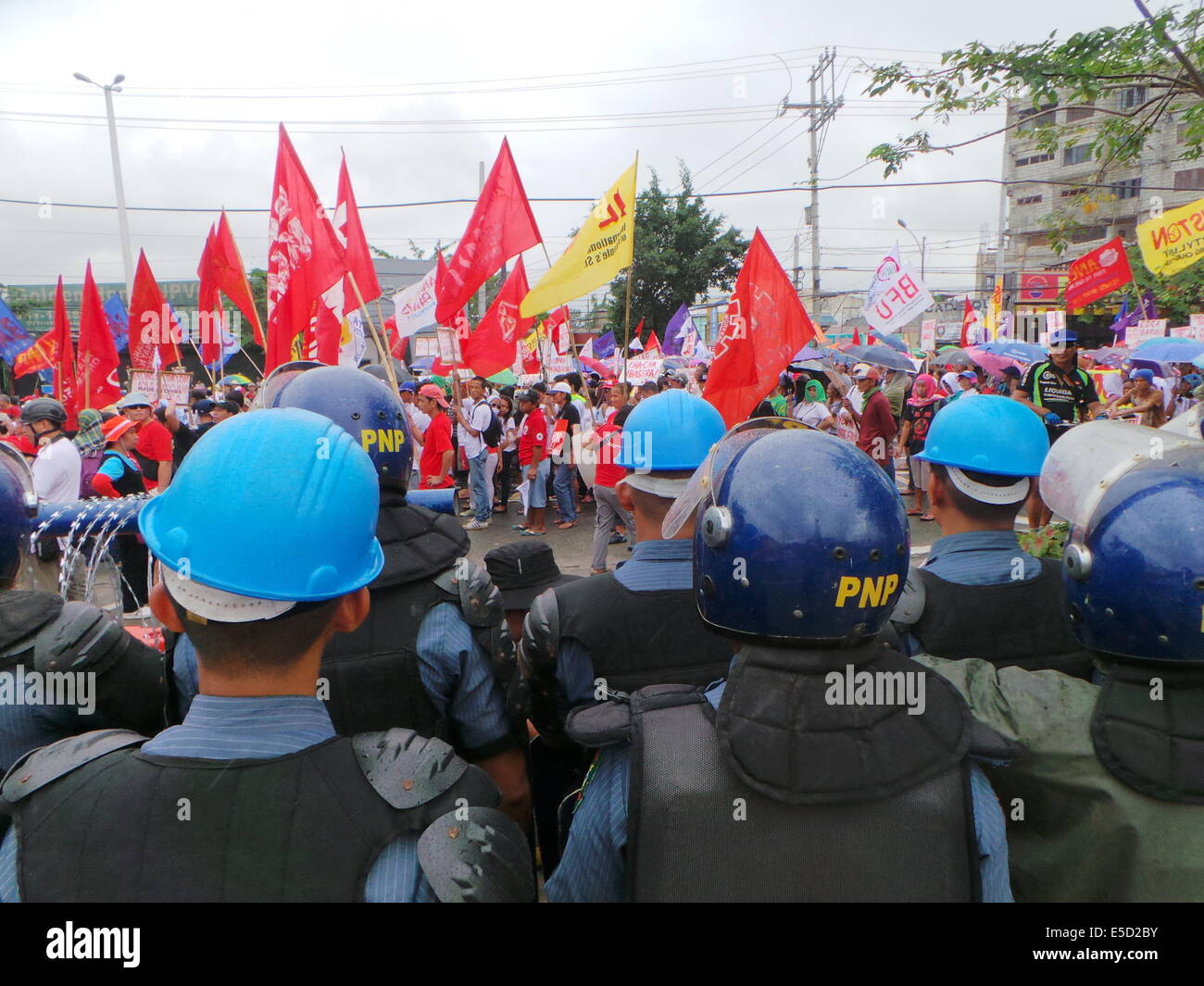 Quezon City, Filippine. 28 Luglio, 2014. Poliziotti monitora i dimostranti durante il quinto membro della Nazione indirizzo (SONA) di Pres. Benigno 'Noynoy' Aquino Jr., come migliaia di gruppi militanti marzo a Batasang Pambansa (casa del rappresentante) nella città di Quezon, con effigi raffiguranti Pres. Aquino come "maiale canna king', e cartelloni tenendo lui responsabile per il saccheggio di P144 miliardi di esborso programma di accelerazione (DAP) fondi che sarebbe stato assegnato a progetti rurali. Credito: Sherbien Dacalanio/Pacific Press/Alamy Live News Foto Stock