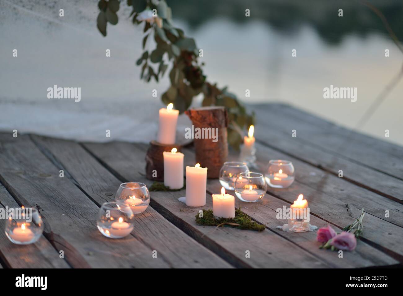 Su un ponte di legno sul fiume al tramonto romantico disposizione delle candele accese Foto Stock