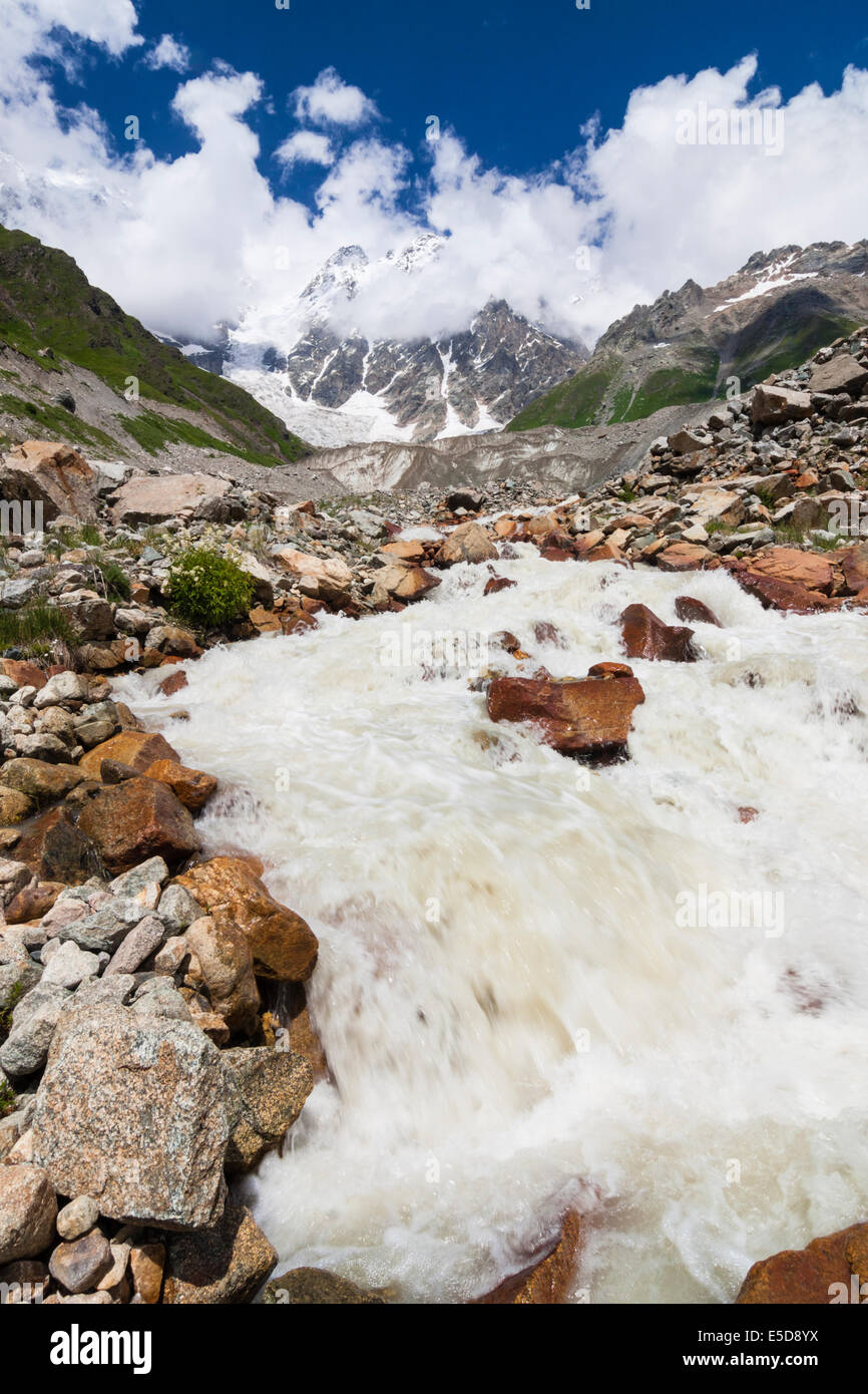 Il torrente a valle Enguri proveniente dal ghiacciaio Shkhara e massiccio, a 5068 m e la vetta più alta in Georgia. Foto Stock