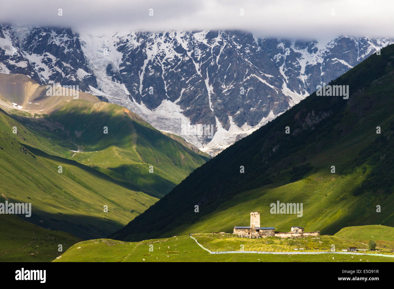 Lamaria chiesa e torre in enormi montagne del Caucaso sfondo. Ushguli, la permanente più alto villaggio abitato in Europa. Foto Stock