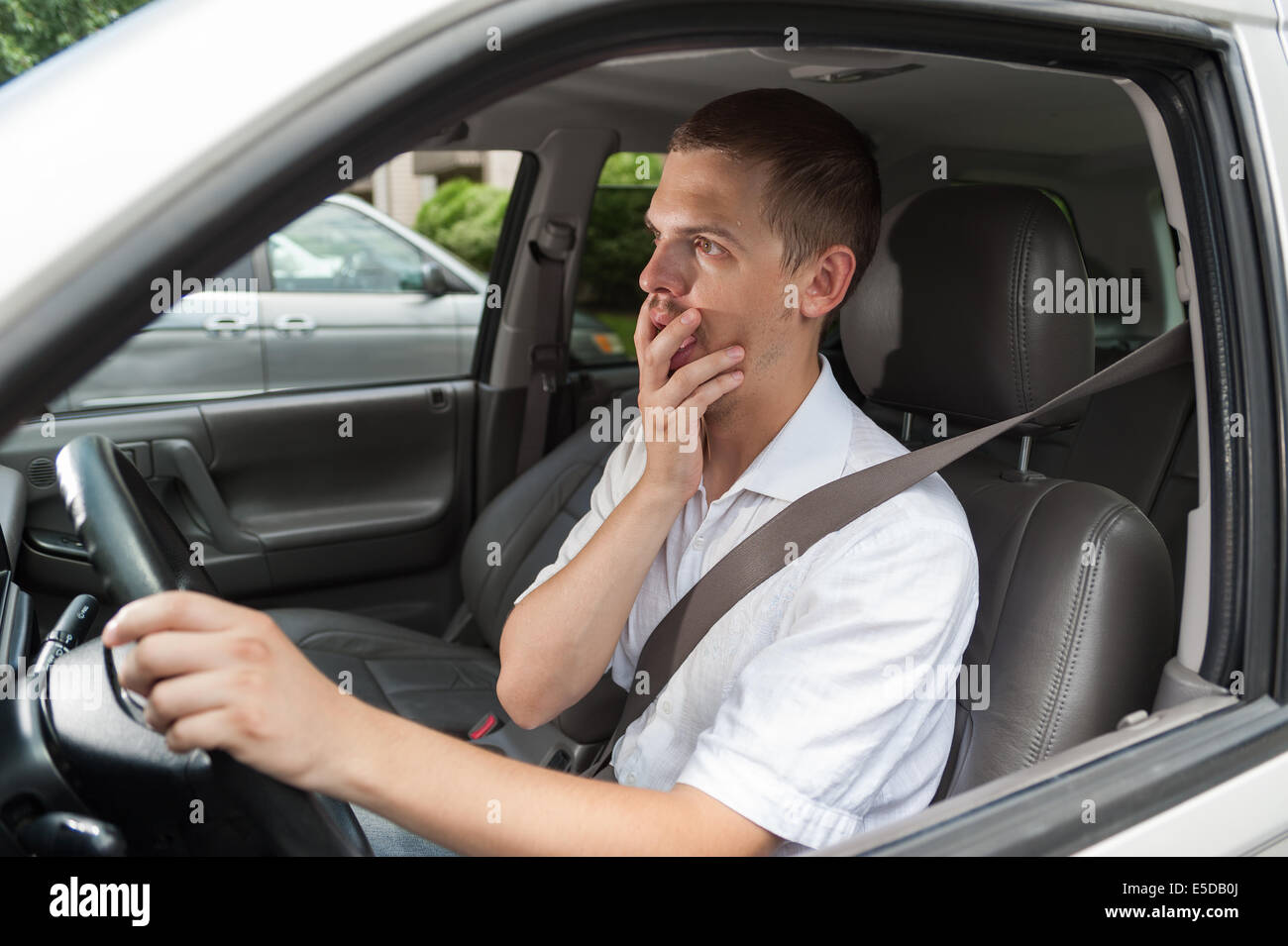 Giovani driver caucasica è sconvolta e tenendo la sua mano sulla sua bocca Foto Stock