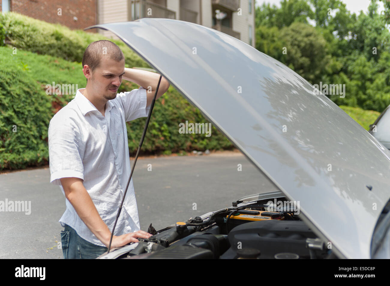 Giovane uomo caucasico è pensare al modo di riparare la sua auto Foto Stock