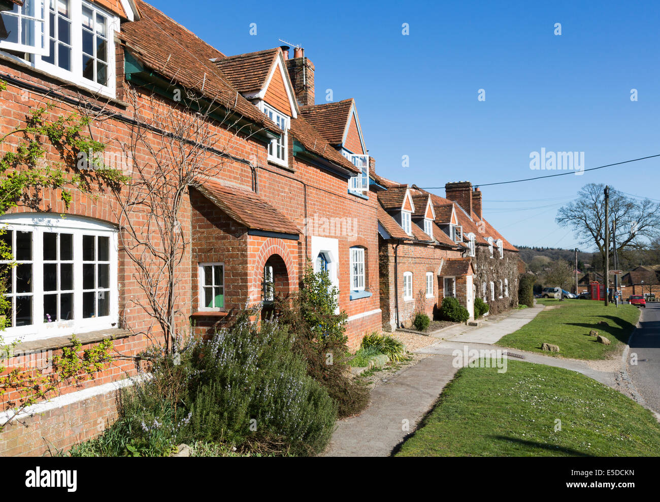 Fila di cottage rurali in mattoni rossi a schiera tradizionale attraente nel villaggio di Great Bedwyn, Wiltshire, Regno Unito in una giornata di sole con un cielo blu Foto Stock