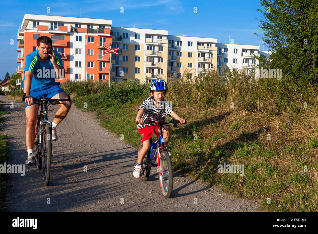 Padre e bambino cavalcano una pista ciclabile per bambini della Repubblica Ceca con casco Foto Stock
