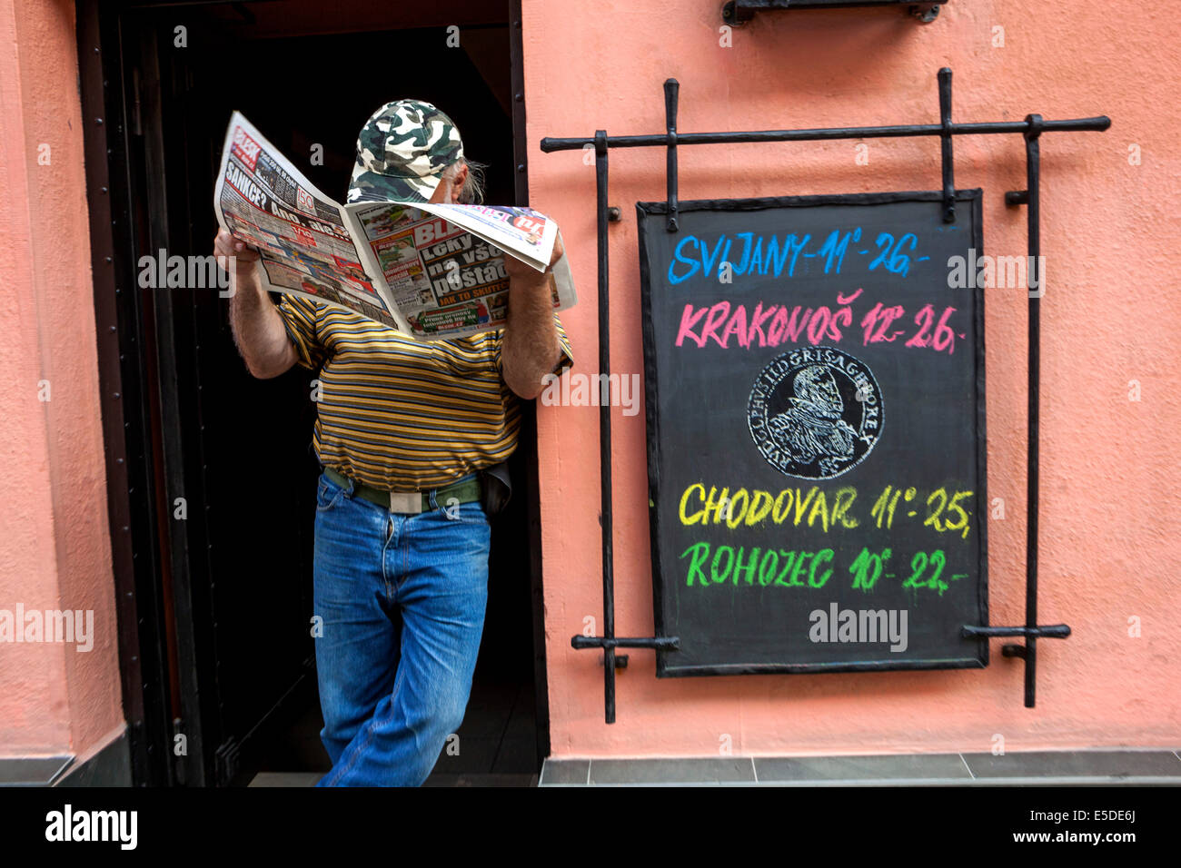 All'ingresso del bar Man che legge un giornale quartiere Zizkov di Praga. Offre quattro tipi di birra con menu a base di gesso Foto Stock