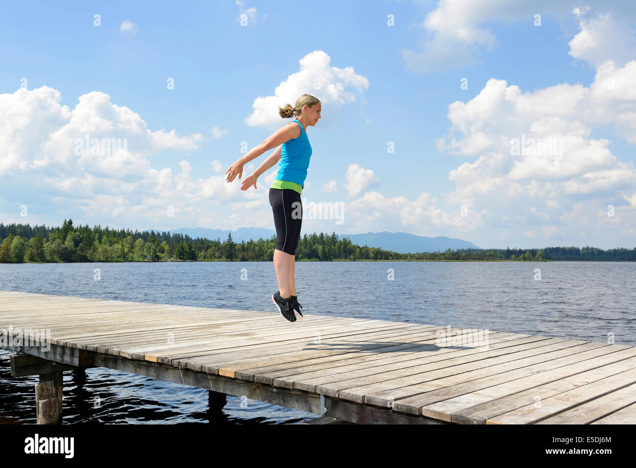 In Germania, in Baviera, Sachsenkam, donna esercizio di allenamento funzionale sul pontile a mare Foto Stock