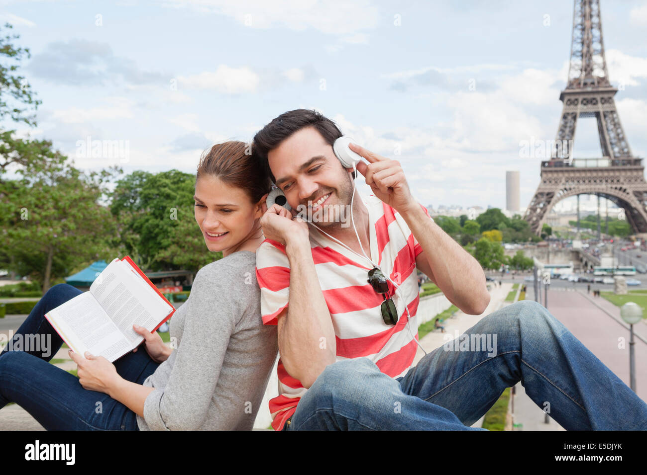 Francia, Parigi, Ritratto di giovane con la guida di viaggio e le cuffie nella parte anteriore della Torre Eiffel Foto Stock