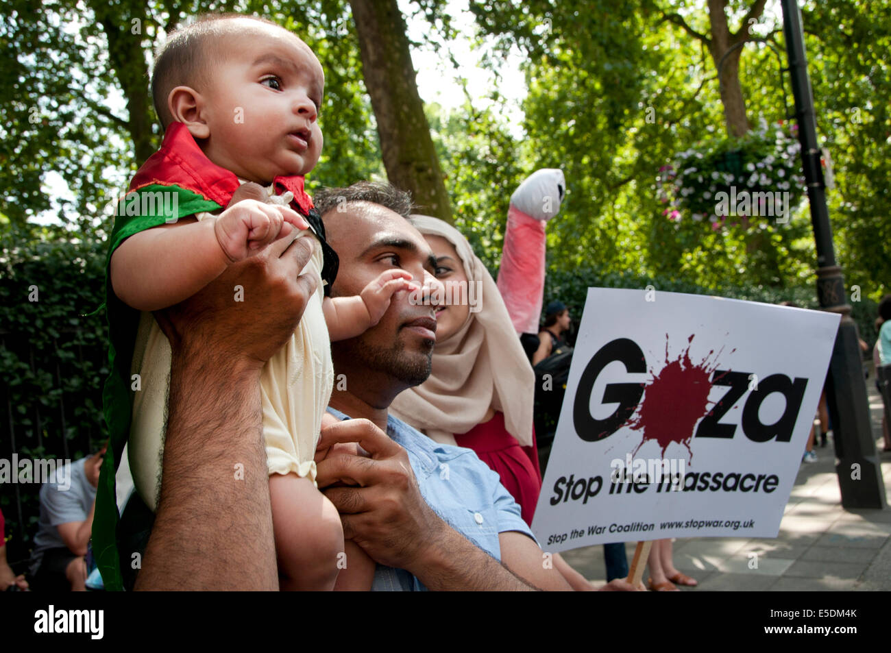 La dimostrazione contro il bombardamento israeliano della Striscia di Gaza, 26.07.2014. Bambino avvolto nella Bandiera palestinese e detenute da suo padre Foto Stock