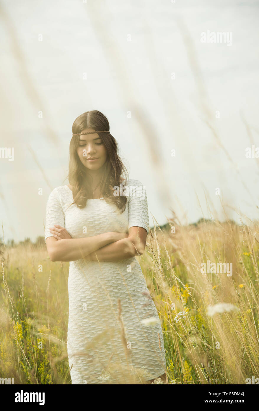 Ritratto di giovane donna con bracci incrociati in piedi sul prato di fiori Foto Stock