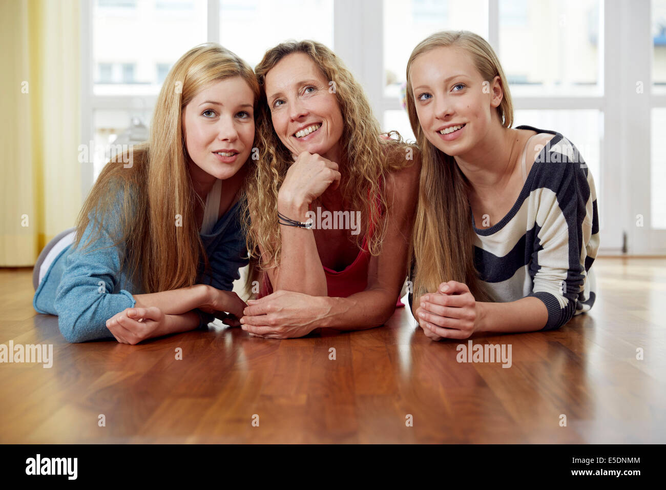 Madre e le sue due figlie sdraiato sul pavimento in legno a casa Foto Stock