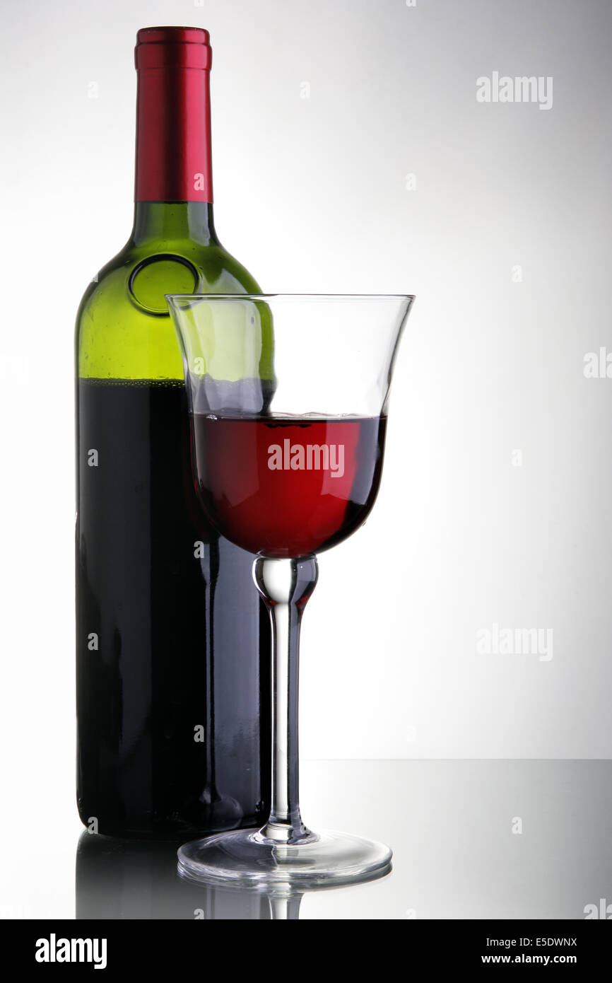 Vetro e una bottiglia di vino rosso su sfondo grigio chiaro Foto Stock