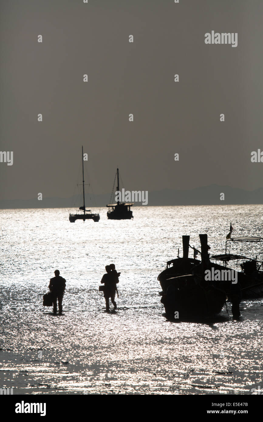 Silhouette di turisti che arrivano in barca a Rai Lae beach, Krabi, Thailandia Foto Stock