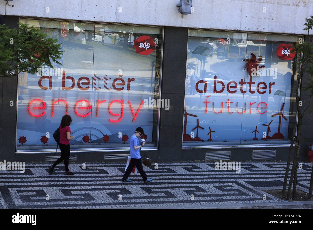 Due persone a piedi i segni del passato nella vetrina di un negozio di EDP potere società raffigurante una migliore energia un futuro migliore, Lisbona Portogallo Foto Stock