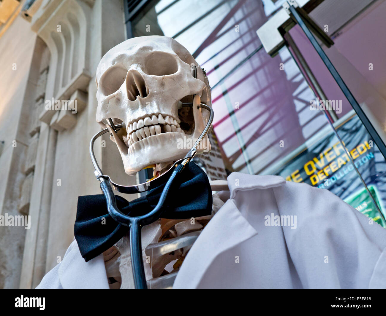 Diagnosi di Covid-19 humorous promemoria di salute personale Coronavirus cura scheletro umano vestito come medico morte con stetoscopio fuori farmacia Foto Stock