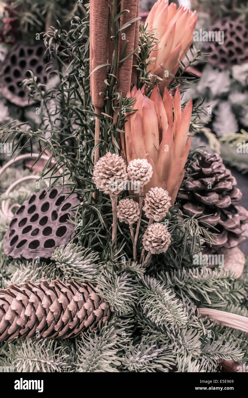 Autunnale di decorazione floreale con coni e rametti di abete rosso in arancio e verde, l'immagine verticale. Foto Stock