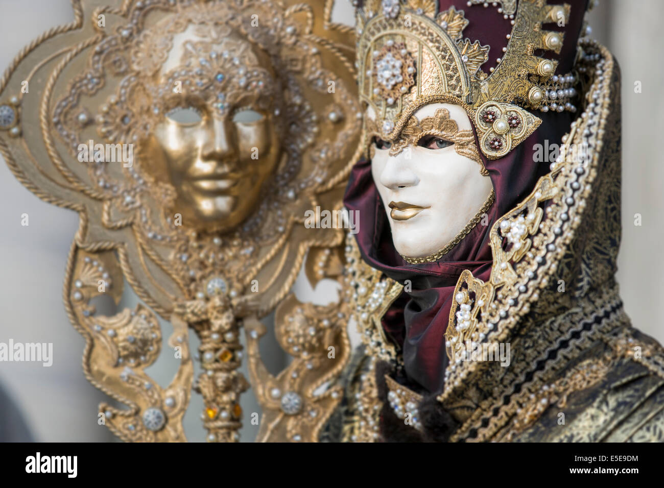 Uomo in nero e oro elaborato costume di carnevale portando la vita dimensioni maschera sul personale in Piazza San Marco, Venezia. Foto Stock