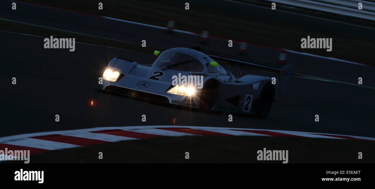 Un argento Mercedes GT auto sportiva racing con i fari accesi al tramonto, durante la Silverstone Classic 2014. Foto Stock