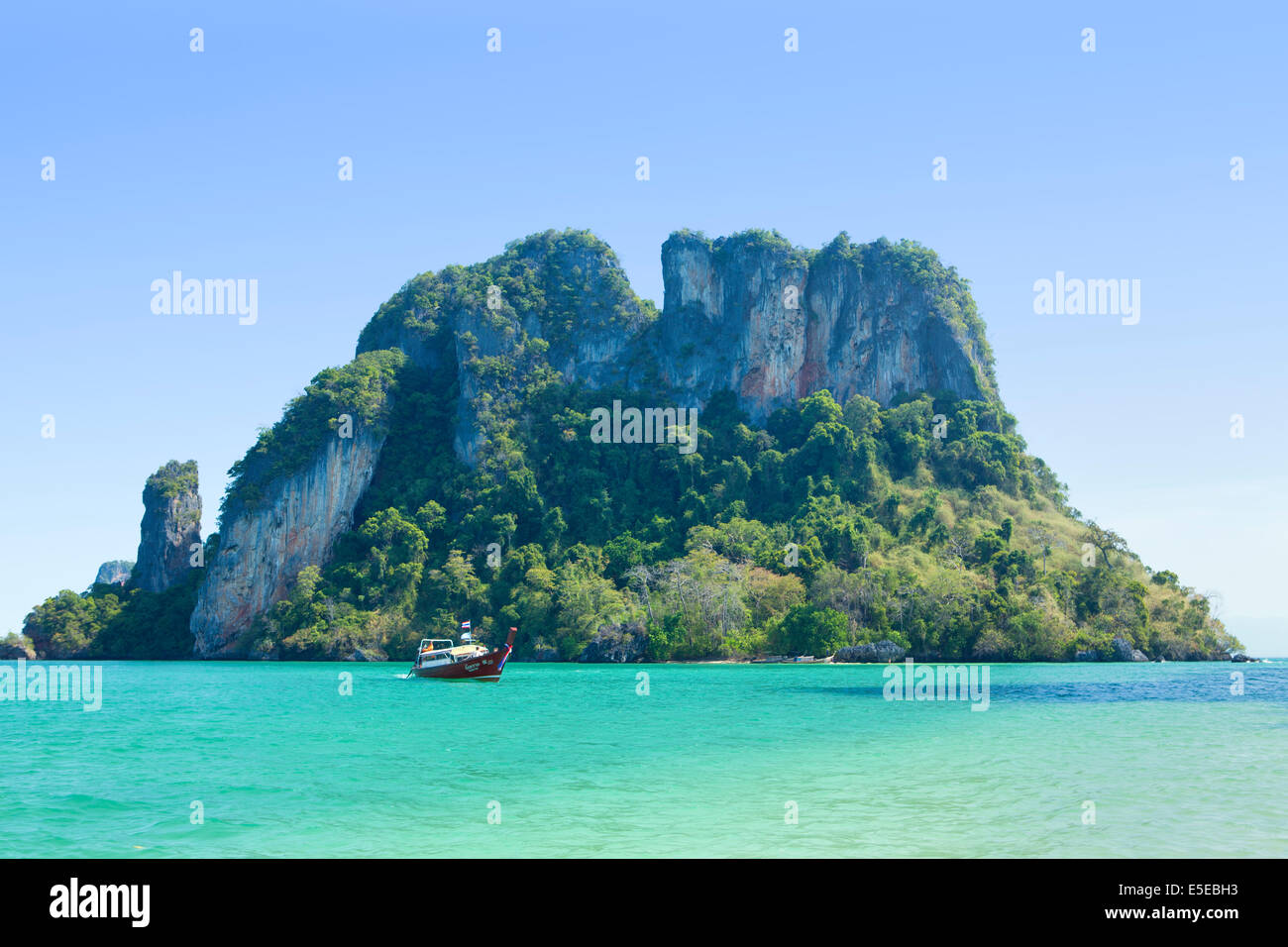 Thai barca dalla coda lunga nella parte anteriore di un'isola scoscese vicino a Krabi, Thailandia Foto Stock